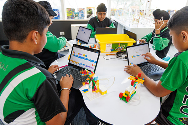 Group of young boys on laptops with lego