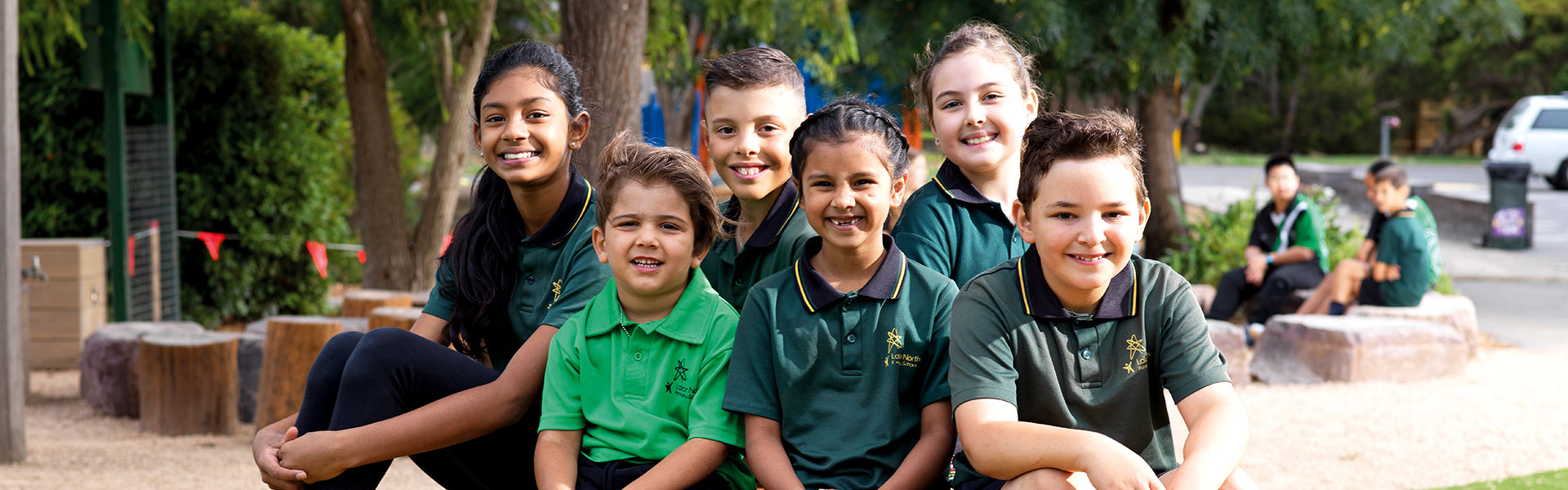 Multicultural group of students sitting outside smiling at the camera